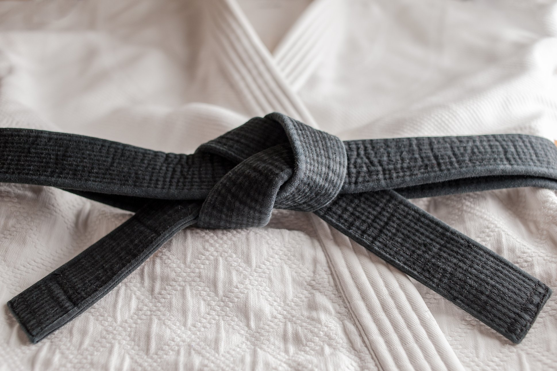 Black judo, aikido, or karate belt on white judo uniform